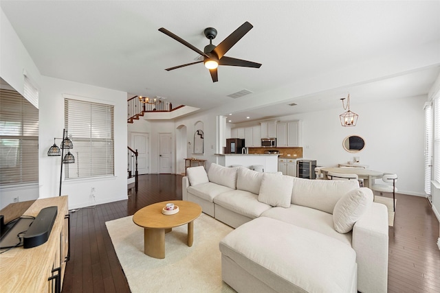 living room featuring wine cooler, wood-type flooring, and ceiling fan with notable chandelier