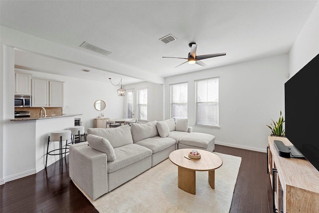 living room featuring dark hardwood / wood-style floors and ceiling fan with notable chandelier