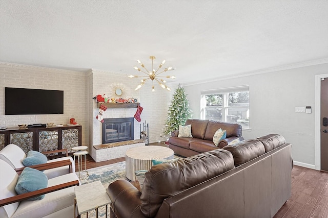 living room with a fireplace, an inviting chandelier, dark wood-type flooring, and ornamental molding