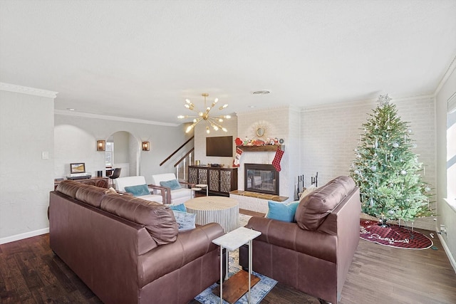 living room with crown molding, a notable chandelier, dark hardwood / wood-style floors, and a large fireplace