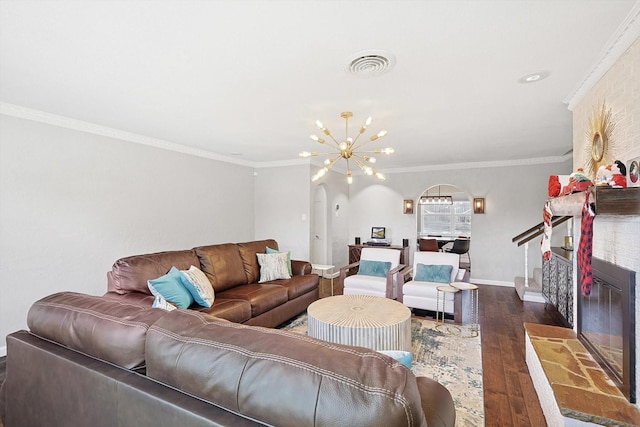 living room with dark wood-type flooring, a large fireplace, ornamental molding, and an inviting chandelier