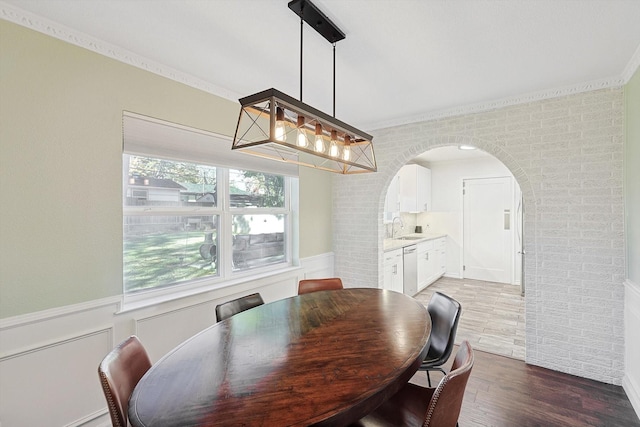 dining space with wood-type flooring, sink, and crown molding