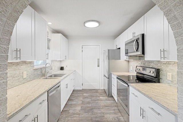 kitchen with white cabinetry, appliances with stainless steel finishes, sink, and light stone counters