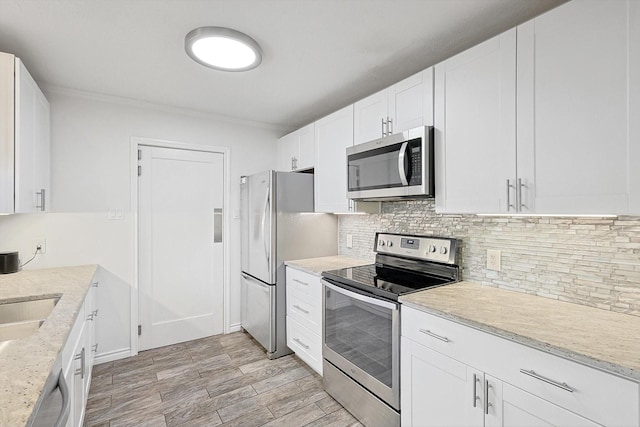 kitchen with white cabinetry, decorative backsplash, light stone counters, stainless steel appliances, and light hardwood / wood-style flooring