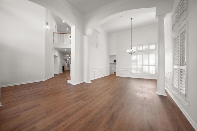 unfurnished living room with decorative columns, ornamental molding, dark hardwood / wood-style floors, and a high ceiling