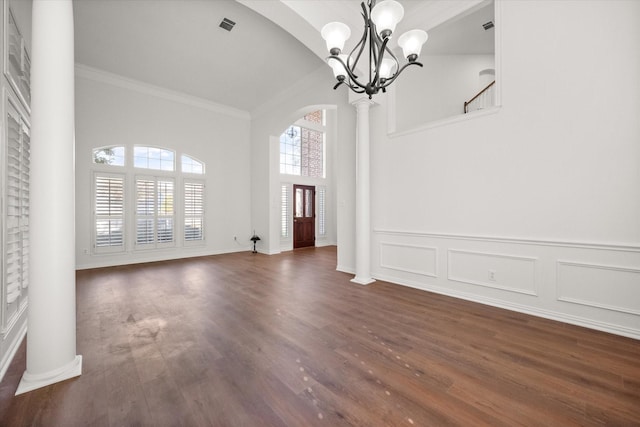 unfurnished dining area with decorative columns, dark wood-type flooring, and a notable chandelier