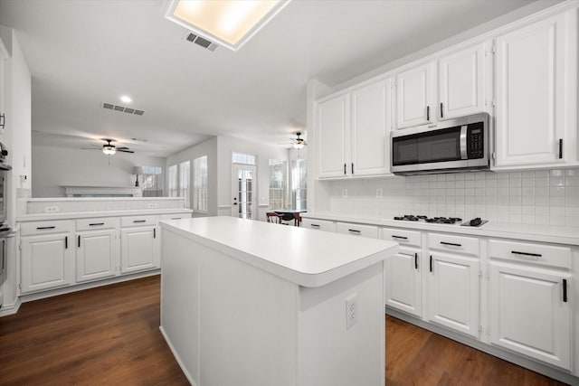 kitchen featuring white gas stovetop, a kitchen island, white cabinetry, ceiling fan, and kitchen peninsula