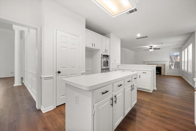 kitchen with a kitchen island, white cabinets, and ceiling fan