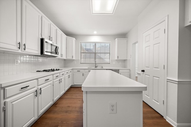 kitchen with white cabinetry, stainless steel appliances, a center island, tasteful backsplash, and dark hardwood / wood-style flooring