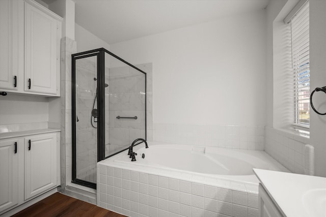 bathroom featuring vanity, wood-type flooring, and plus walk in shower