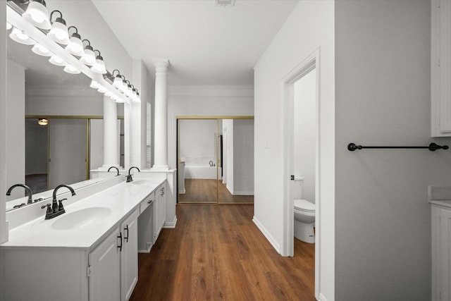 bathroom featuring toilet, ornamental molding, vanity, hardwood / wood-style floors, and decorative columns