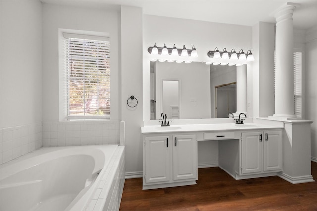 bathroom featuring a relaxing tiled tub, vanity, hardwood / wood-style flooring, and ornate columns