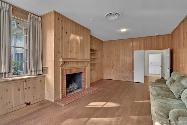 living room with a fireplace, light hardwood / wood-style flooring, built in features, and wooden walls