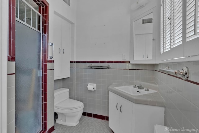 bathroom featuring tile patterned flooring, vanity, tile walls, and toilet