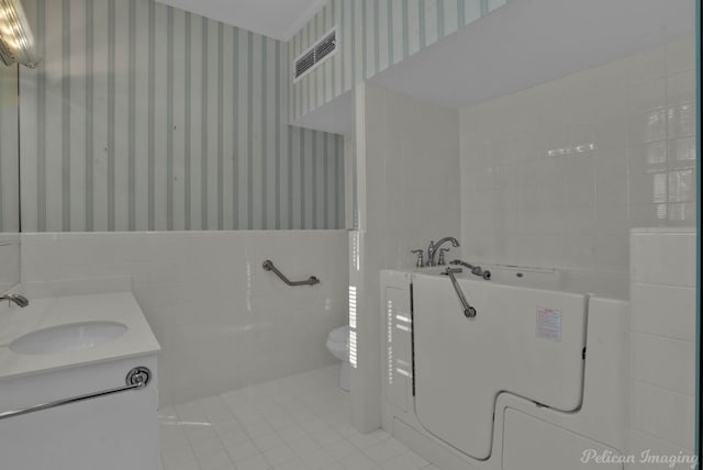 bathroom featuring tile patterned flooring, vanity, tile walls, and toilet