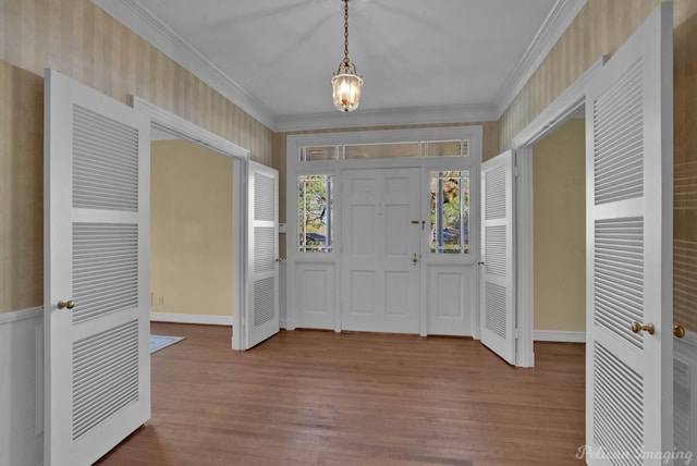 entryway with crown molding, a notable chandelier, and hardwood / wood-style flooring