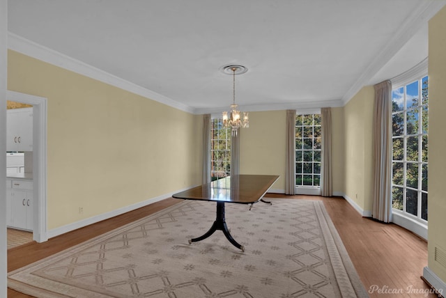 unfurnished dining area featuring wood-type flooring, crown molding, and a notable chandelier