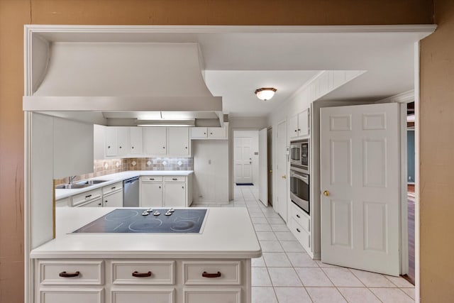 kitchen with appliances with stainless steel finishes, tasteful backsplash, light tile patterned floors, a sink, and a peninsula