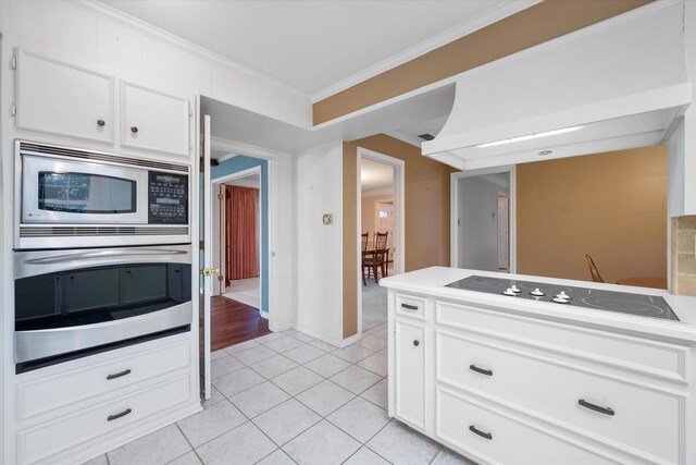 kitchen with white cabinets, stainless steel appliances, crown molding, and light tile patterned floors