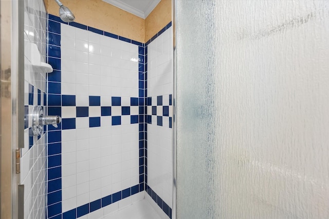 bathroom with ornamental molding and a tile shower