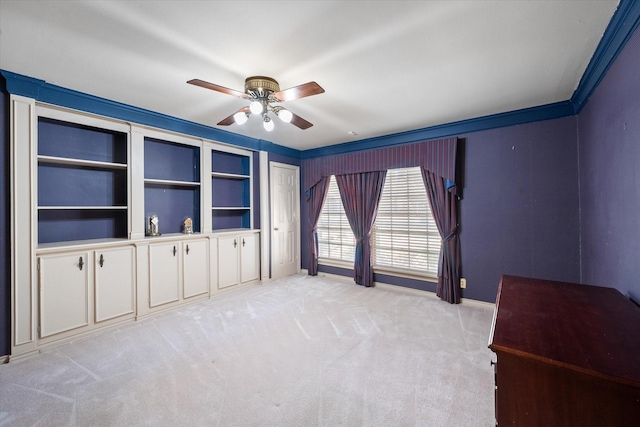 interior space featuring baseboards, a ceiling fan, crown molding, and light carpet