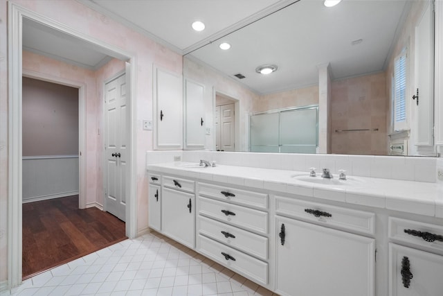 full bathroom featuring double vanity, visible vents, crown molding, a stall shower, and a sink