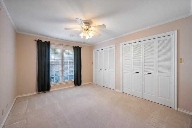 unfurnished bedroom featuring multiple closets, ornamental molding, and carpet floors