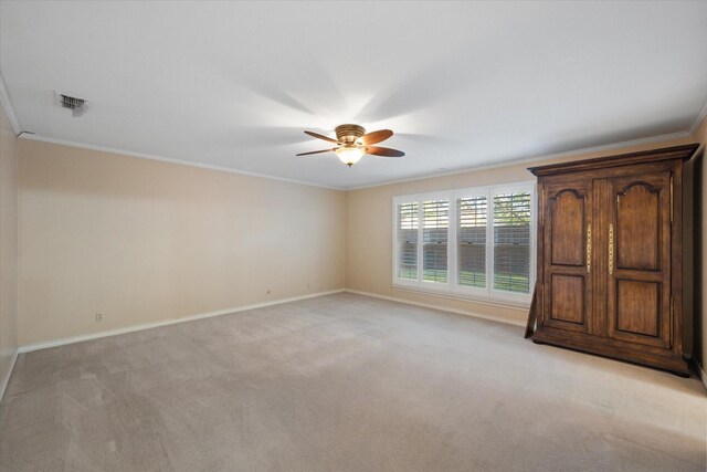 spare room featuring ceiling fan, visible vents, crown molding, baseboards, and light carpet