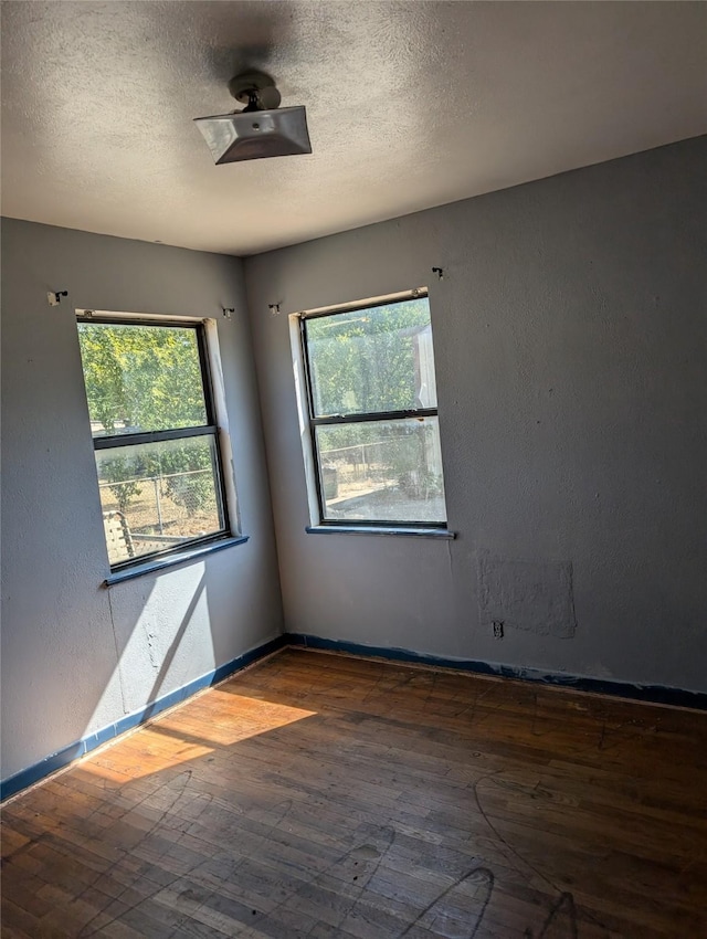 empty room with dark wood-type flooring and a textured ceiling