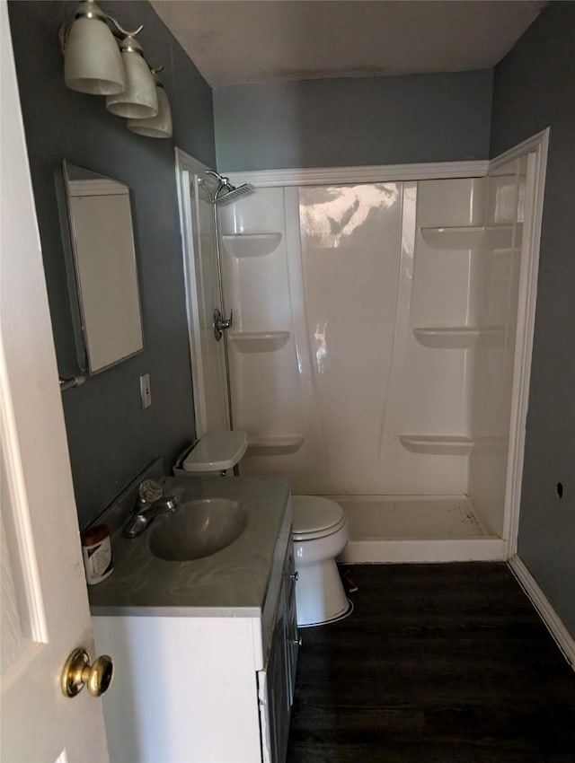 bathroom with hardwood / wood-style flooring, vanity, toilet, and walk in shower