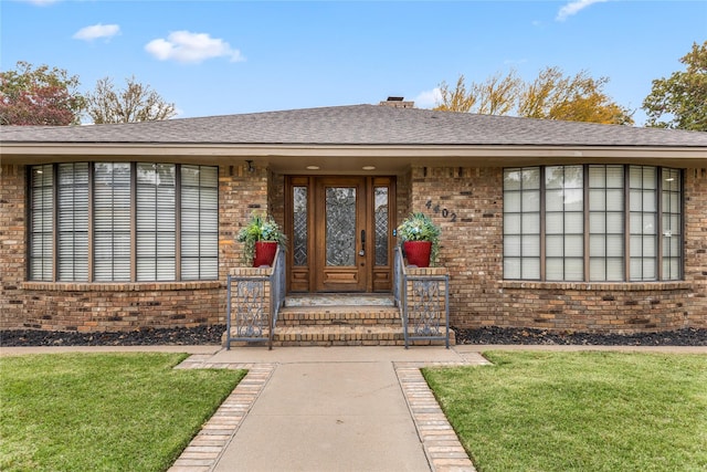 view of exterior entry featuring a lawn