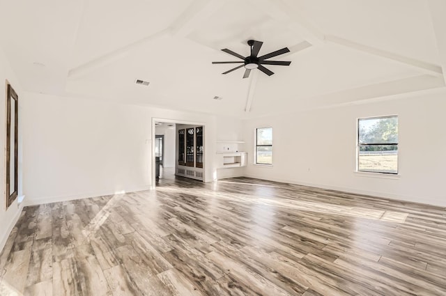 unfurnished living room with beam ceiling, hardwood / wood-style flooring, ceiling fan, and a healthy amount of sunlight