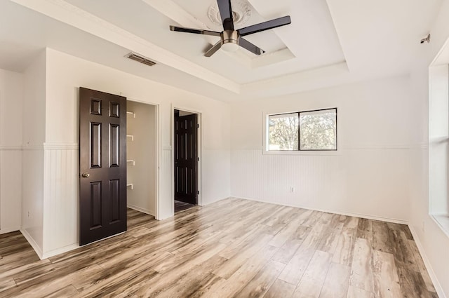 unfurnished room featuring light hardwood / wood-style floors, ceiling fan, and a tray ceiling