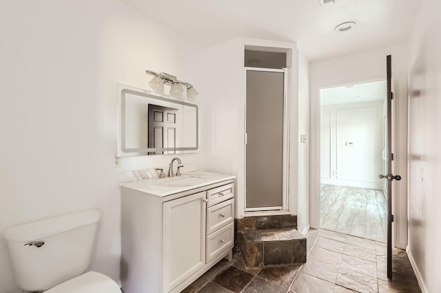 bathroom featuring vanity, toilet, and a shower with door