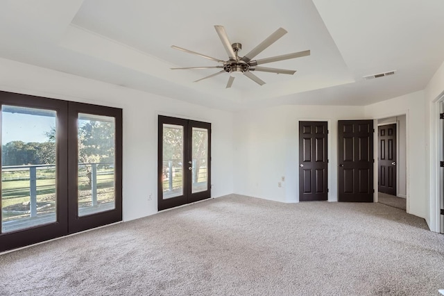 spare room with carpet flooring, ceiling fan, a raised ceiling, and french doors