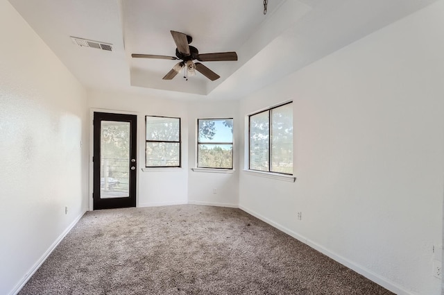 carpeted spare room with ceiling fan and a raised ceiling