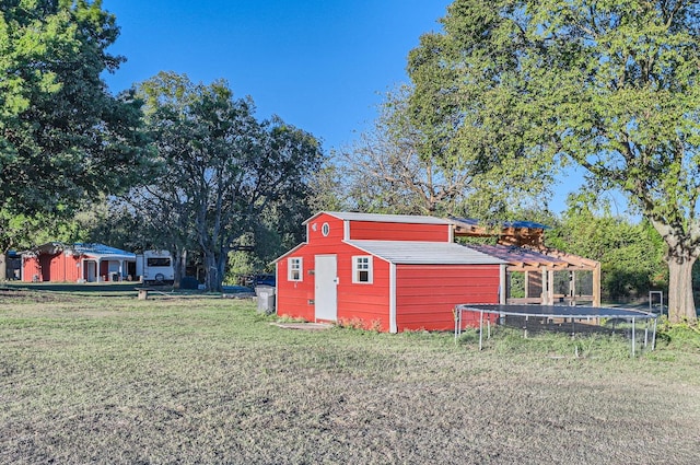 view of outbuilding with a lawn and a trampoline