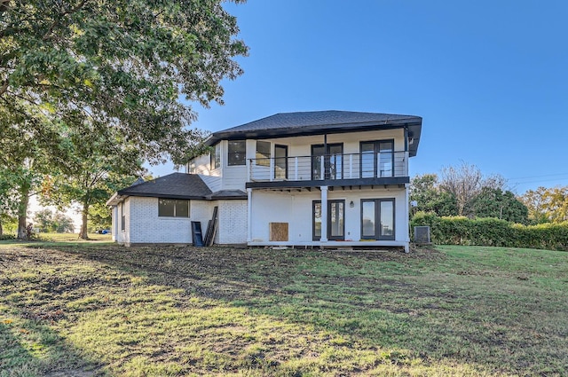 rear view of property with a balcony and a yard