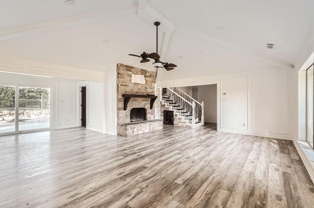 unfurnished living room featuring a fireplace, light hardwood / wood-style flooring, high vaulted ceiling, and beamed ceiling