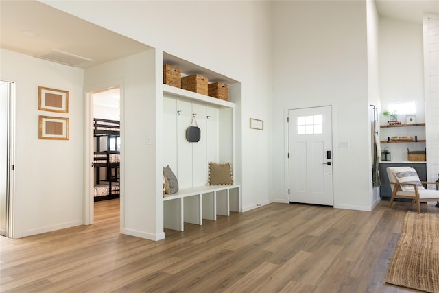 mudroom with hardwood / wood-style floors and a high ceiling