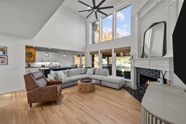 living room with ceiling fan, a fireplace, vaulted ceiling, and light wood-type flooring