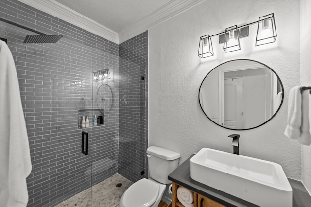 bathroom with crown molding, tiled shower, vanity, and toilet