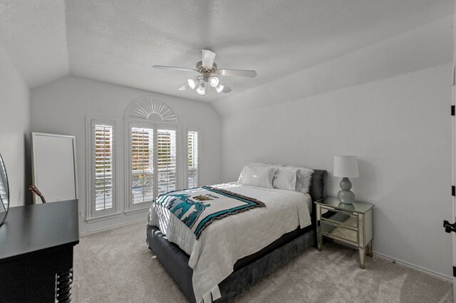 bedroom with lofted ceiling, light colored carpet, a textured ceiling, and ceiling fan