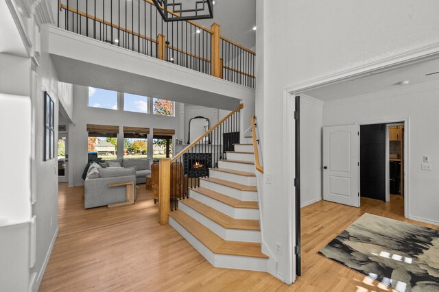 stairway with hardwood / wood-style floors, a towering ceiling, and crown molding