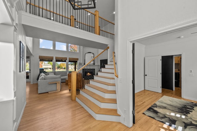 stairs with hardwood / wood-style flooring, ornamental molding, and a high ceiling