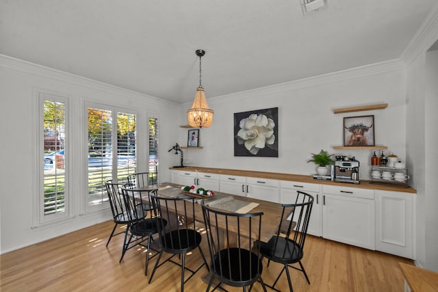 dining room with ornamental molding, a chandelier, and light hardwood / wood-style flooring