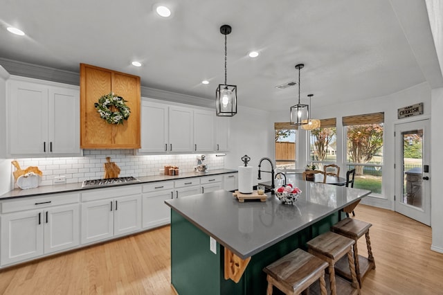 kitchen featuring white cabinetry, decorative light fixtures, and a kitchen island with sink