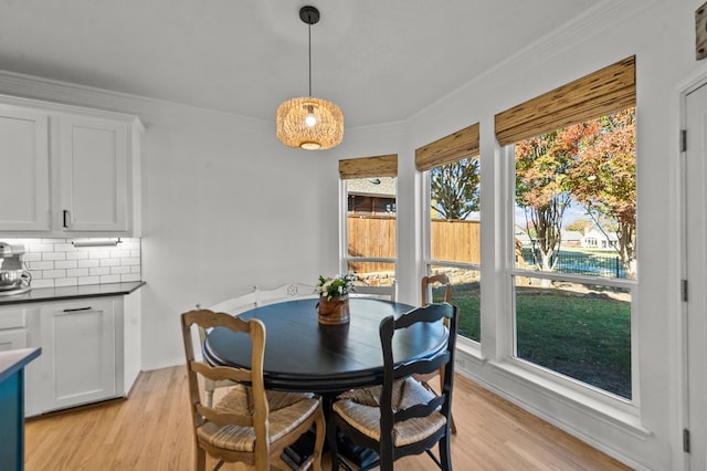 dining room with crown molding and light hardwood / wood-style flooring