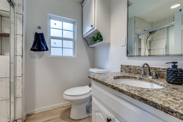 bathroom with wood-type flooring, vanity, toilet, and a shower with shower door