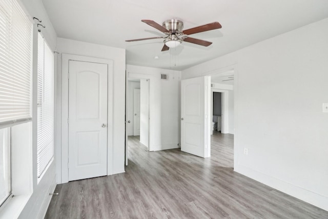 unfurnished bedroom featuring a ceiling fan, light wood-style flooring, visible vents, and baseboards